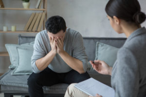 Adult man sitting upset discussion with psychologist mental health care